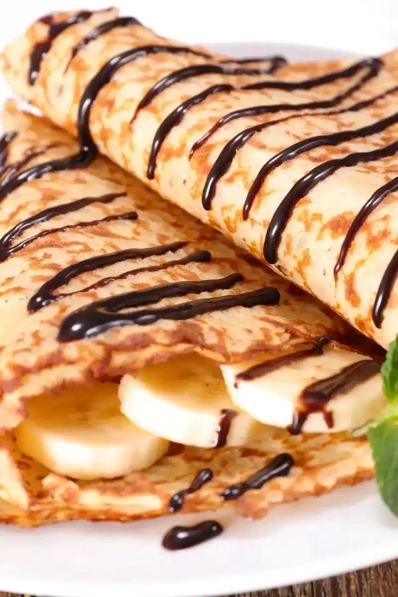 Gefaltete pfannkuchen ohne ei mit Bananenscheiben und Schokoladensauce